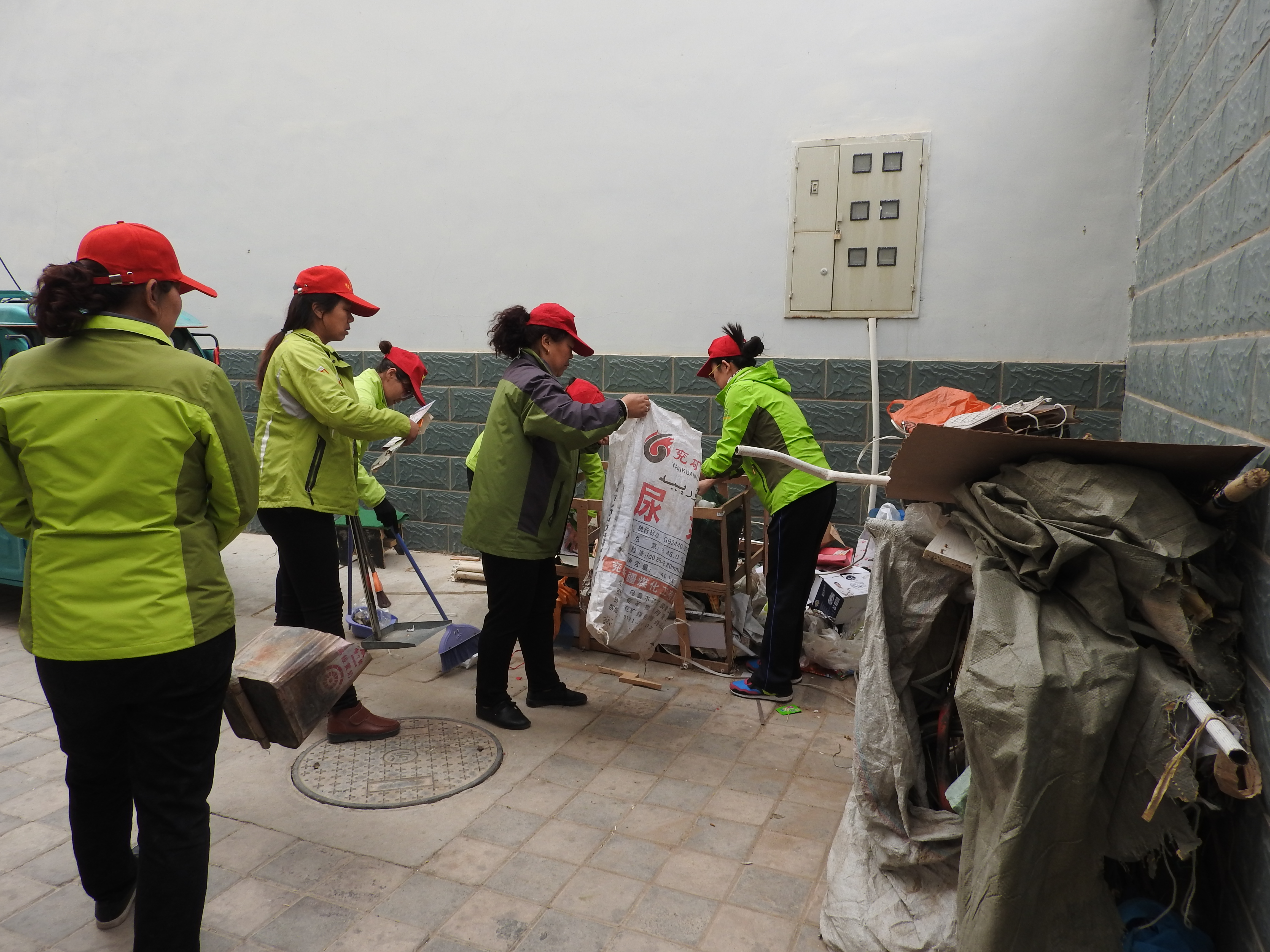 图为：绿色志愿者服务队为居民打扫楼院.JPG